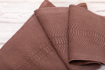 brown suede dyed genuine natural python leather on the wooden table	
