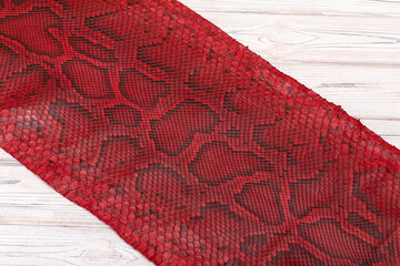 red spotted dyed folded natural genuine python leather on the wooden table	