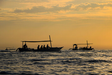 silhouette of fishing boat crossing the sea at sunset