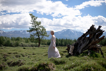 Fototapeta na wymiar a girl in a royal image, a girl walks against the backdrop of mountains, a girl in a gray dress