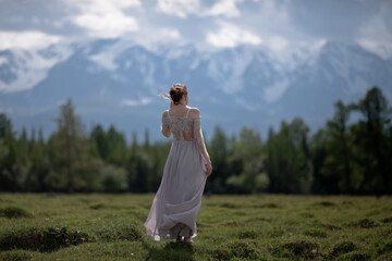 Obraz premium a girl in a royal image, a girl walks against the backdrop of mountains, a girl in a gray dress