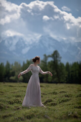 Fototapeta na wymiar a girl in a royal image, a girl walks against the backdrop of mountains, a girl in a gray dress