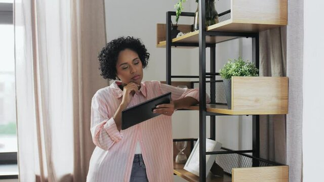 home improvement, technology and people concept - woman with tablet pc computer standing at shelf and thinking