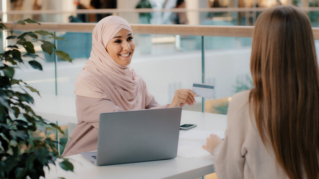 Muslim financial advisor banking worker giving credit card unrecognizable girl client signs contract for approval of bank loan takes mortgage arab manager talks about benefits of contactless payment