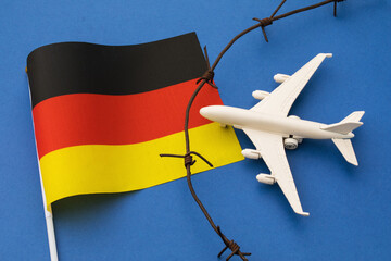 Germany flag, barbed wire and toy plane on blue background, state air border violation concept