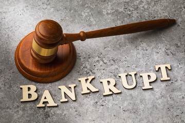An inscription of wooden letters and a judge hammer on the table, the concept of bankruptcy