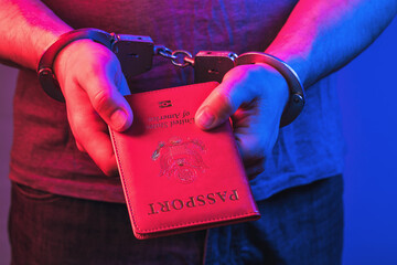 Hands in handcuffs with an American passport, the concept of punishment for fake documents - obrazy, fototapety, plakaty