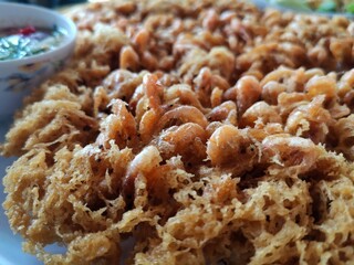 Thai food, crispy little shrimp and dipping sauce are on the plate.
