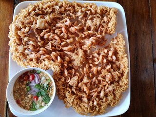 Thai food, crispy little shrimp and dipping sauce are on the plate.
