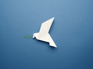 White origami pigeon on a blue paper background, peace or freedom concept - obrazy, fototapety, plakaty