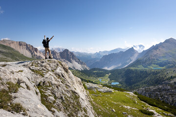 Hiker with raised arms next to a scenic mountain landscape