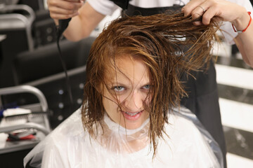 Fototapeta premium Hairdresser using hairdryer for treatment with hair, dry wet hair after beauty procedure
