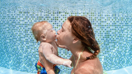 Happy family - young mother, baby boy learn to swim, hold breath, dive underwater. Fun in swimming pool. Healthy lifestyle, active parents, people water sports activities on summer holidays with kids.