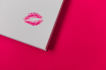  Imprint of female lips on white paper on a pink background. kiss on paper. Love message. High quality photo