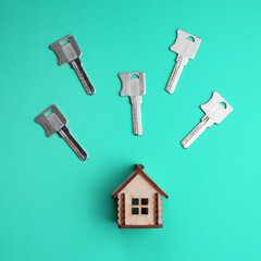 Conceptual composition: a wooden model of a house and a set of house keys on a colored background. Buying, selling, renting real estate. Fashionable colorful photo. Trendy flat lay concept.