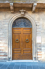 Vintage front door in the medieval city of Italy. Ancient streets of the city, beautiful doors and unusual door handles in the shape of a lion's head.
