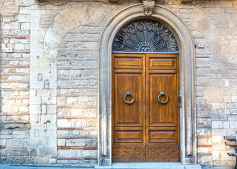 Fototapeta na wymiar Vintage front door in the medieval city of Italy. Ancient streets of the city, beautiful doors and unusual door handles in the shape of a lion's head.