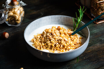 Delicious yogurt with granola and nuts served on dark table, closeup. Oatmeal granola. Baked granola with nuts. Healthy breakfast. Vegan granola.