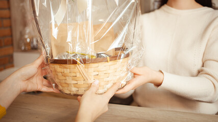 seller sells gift set, festive packaging. woman buys basket with gift in tea shop. Private medium business, individual entrepreneur. closeup