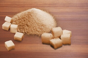 Pile of brown granulated sugar and sugar cubes on the desk