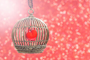 Red heart inside a birdcage on pink