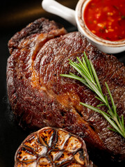 Close up beef meat  steak grill with herbs rosemary, garlic and sauce on black background, macro overlay, flat lay, top view - 481114713