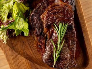 Beef steak grill with herbs rosemary, garlic and sauce on black background. Top view overlay, close up - 481114722