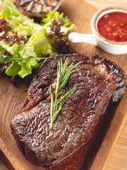 Beef steak grill with herbs rosemary, garlic and sauce on black background. Top view overlay, close up - 481114724