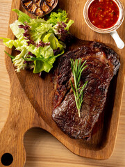 Beef steak grill with herbs rosemary, garlic and sauce on black background. Top view overlay, close up - 481114725