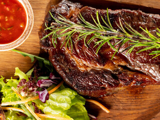 Beef steak grill with herbs rosemary, garlic and sauce on black background. Top view overlay, close up - 481114726