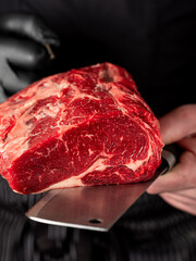 Close up beef meat in chef butcher's hands with knife on black background - 481114733