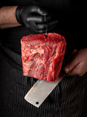 Close up beef meat in chef butcher's hands with knife on black background - 481114735