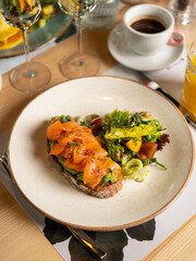 Avocado toast - sandwich with guacamole and salmon fish on bread. Breakfast dish menu served in restaurant background 