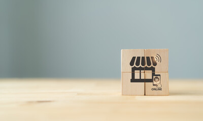 Online shopping and online marketing concept. The wooden cubes with shop and online purchasing icons on grey background and copy space. Marketing and sales channel strategy. E-commerce concept.
