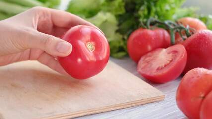woman holding fresh juicy tomatoes hands close up, vegetables and and lettuce on background