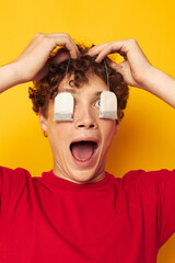 Young curly-haired man posing tea disposable bags yellow background unaltered