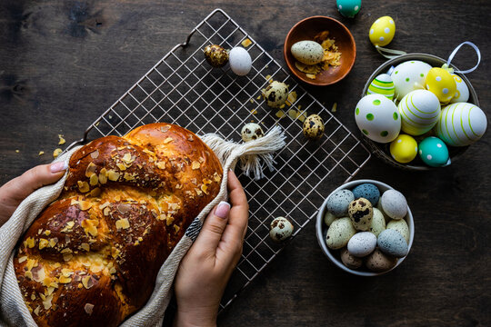 Close-up of a woman placing a traditional tsoureki Easter loaf with almonds on a cooling rack