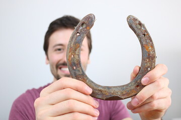 Young caucasian man showing Horseshoe. Being lucky concept. 