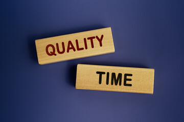 Wooden blocks form the words 'Quality time ' on a dark blue background. Evaluation of goods or services business concept