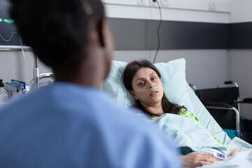 Over shoulder view of patient with nasal cannula recieving oxygen recovering on hospital bed...