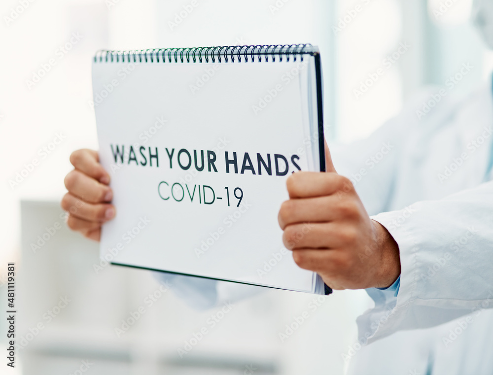 Poster practicing hand hygiene helps. shot of a scientist holding a sign with wash your hands on it in a la