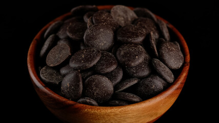Dark chocolate chips in wooden bowl. Confectionery concept.