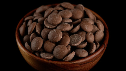 Milk chocolate chips in wooden bowl. Confectionery concept