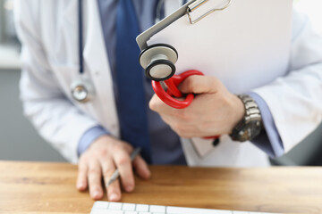 Doctor holding medical equipment red stethoscope and patient medical history