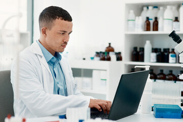 Keep calm, the cure is coming. Shot of a young scientist using a laptop while working in a laboratory.