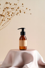 Blank brown amber glass bottle with label mockup and dry flowers on beige background. Soap...