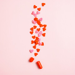 Split pill with hearts on pink background. Love pill tablet capsule concept.