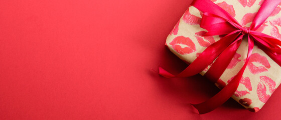 Valentines Day gift box wrapped craft paper with lipstick marks print with red ribbon bow on red...