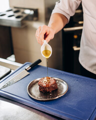 Chef pouring olive oil onto raw meat. Seasoning beef steak with pepper, salt, garlic, lime and...