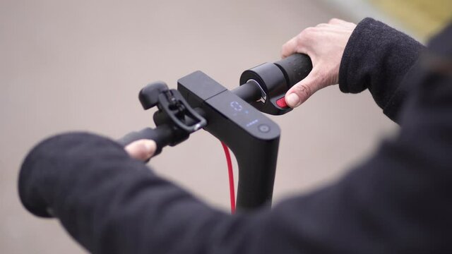 Close-up top view 4k stock video footage of hands of anonymous young woman and steering wheel of modern electric scooter. Person having fun outdoors driving scooter